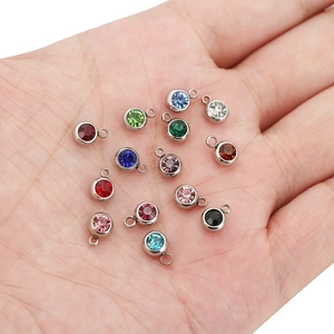 Hand holding various colorful stainless steel birthstone charms for DIY jewelry making