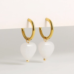 Detail of 18K gold-plated hoop earrings featuring elegant white heart stone pendants