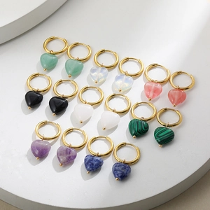 Detailed view of multiple heart-shaped stone pendant earrings in various colors and gold finish