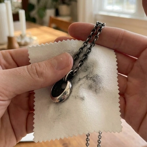 Polishing a retro silver drop pendant necklace with a 8x8cm white jewelry cleaning cloth