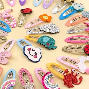 Close-up of children's cartoon hair clips featuring glitter elephants and rainbow designs