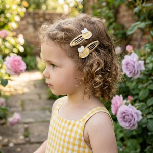 Close-up of cute bee hair clips with yellow glitter and fabric wings on a young girl
