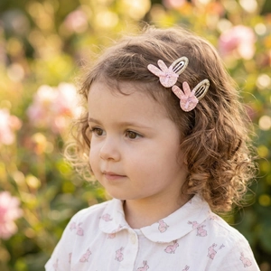 Close-up of pink sequin bunny hair clips worn by a girl in a soft garden setting