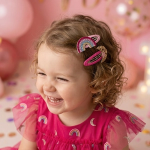 Close-up of glittery rainbow and star hair clips worn by a young girl for parties