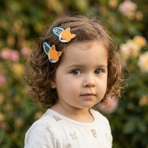 Close-up of a child wearing a cute orange felt fox hair clip in an outdoor garden