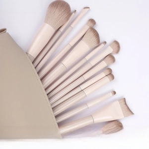 Detailed flat lay of 13 pieces beige makeup brush set with matching leather pouch