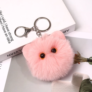 Close-up of pink fluffy cat head keychain with orange eyes and silver metal lobster clasp