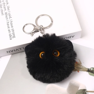 Close-up of soft black fluffy cat plush keychain with big eyes and silver metal clasp