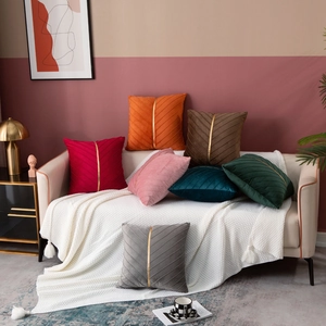 Detail of velvet pillow covers with quilted texture and gold metal strip decor