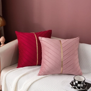 Detail of luxury velvet throw pillows featuring pleated texture and golden metallic ribbon