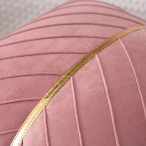 Detail of pink velvet pillowcase featuring quilted texture and a gold decorative metallic strap