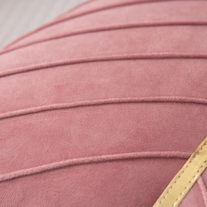 Macro detail of pink velvet cushion showing horizontal stitching and gold leather piping
