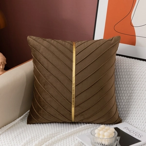 Close-up of brown velvet cushion with V-shaped pleated design and gold ribbon detail