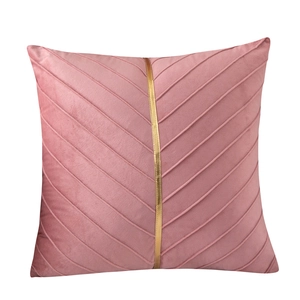 Modern pink velvet decorative pillow with V-shaped pleats and golden vertical metal trim