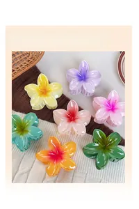 Colorful gradient plumeria hair claw clips in assorted shades on soft knit background