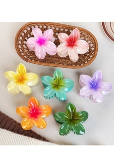 Detailed top view of colorful plumeria hair claws in seven vibrant gradient shades
