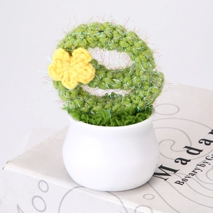 Hand-crocheted cactus plant with yellow flower in a white ceramic pot for desk decor