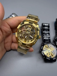 Detailed close-up of a skeleton automatic mechanical watch with gold and black steel strap