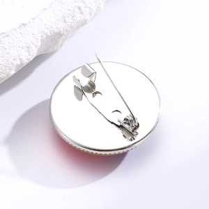 Macro shot of silver metal brooch back showing secure safety pin and smooth finish