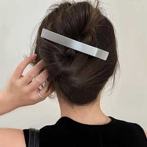 Macro view of a large silver brushed metal hair clip securing a stylish updo hairstyle