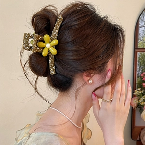 Detail of a large green floral Mori style hair claw clip on a woman's brown bun