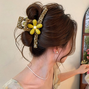 Close-up of a large floral hair claw clip worn on a bun, showcasing fabric and flower detail