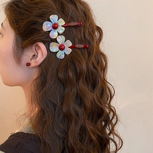 Detailed side view of iridescent resin flower hair clips styled on wavy brown hair