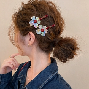 Close-up detail of iridescent resin flower hair clip styled on a model's brown hair bun