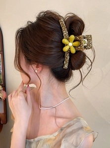 Close-up detail of a large green floral hair claw clip used in an elegant updo.