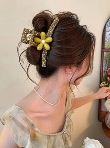 Detailed view of a forest-style floral hair claw clip worn on an elegant bun.