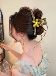 Detailed side and back view of a forest style floral hair claw clip worn in a bun hairstyle