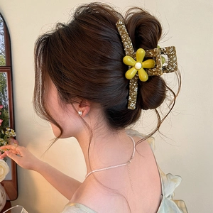 Close-up detail of a large floral hair claw clip styled in an elegant feminine updo