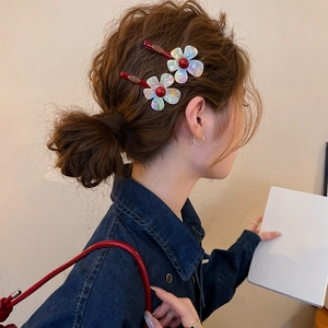 Close-up view of two iridescent resin flower hair clips worn on a model's side hair.