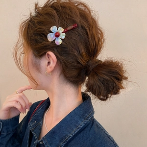 Detailed macro view of an iridescent resin flower hair clip styled on a messy bun