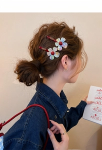 Close-up detail of stylish iridescent resin flower hair clips on a model's side hair.