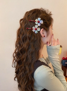 Iridescent resin flower hair clips stylishly worn on long wavy brown hair for a sweet look