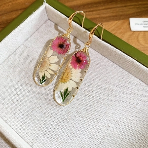 Primo piano di orecchini in resina in stile pastorale con veri fiori essiccati