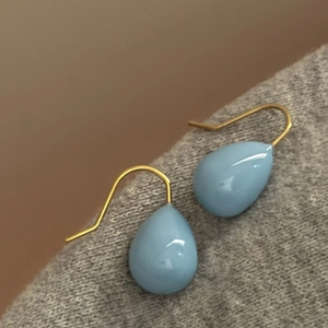 Gros plan détaillé de boucles d'oreilles en verre bleu clair en forme de goutte