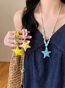 Detail of dopamine-style colorful starfish beaded necklaces on a model for seaside vacation