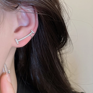 Macro view of a shimmering silver zircon-encrusted bar ear cuff worn on the ear