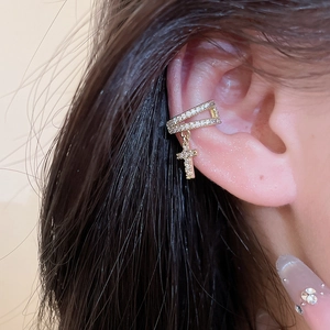 Macro view of a stylish gold cross dangle ear cuff set with sparkling zircon stones