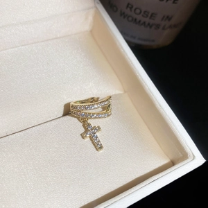 Detail shot of a gold-plated ear cuff with sparkling zircon cross charm in a jewelry box