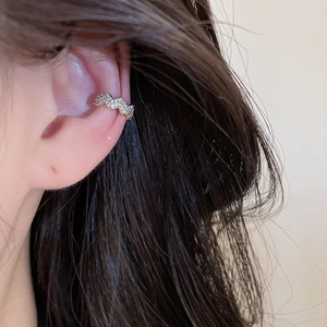Detailed macro view of a sparkling zircon wavy ear cuff for non-pierced ears on a model