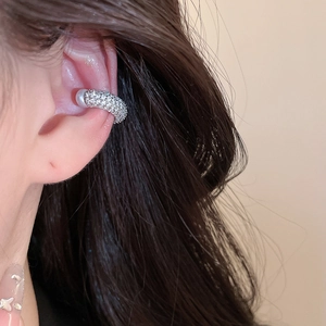 Close-up of elegant silver zircon paved ear cuff with pearl accent worn on ear cartilage