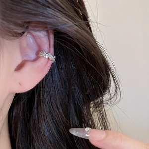 Close-up of a sparkling zircon wavy ear cuff worn on the ear bone without piercing