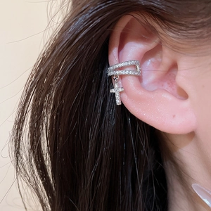 Close-up detail of a stunning silver-toned zircon-encrusted dangling cross ear cuff