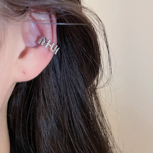 Detailed view of a silver-toned zircon-inlaid non-pierced ear cuff on model's ear