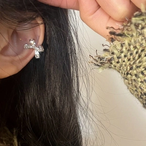 Detailed view of an elegant sparkling bowknot crystal ear cuff worn on the ear bone.