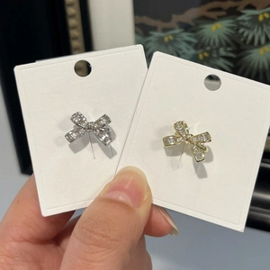 Close-up detail of luxury bow-knot ear cuffs in gold and silver finish on white cards