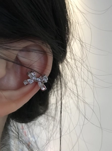 Close-up of an elegant silver bow-knot ear cuff with shimmering crystals on ear.
